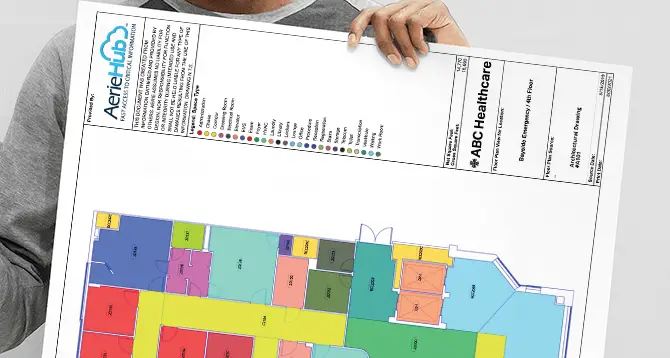 a person holding in front a floor plan