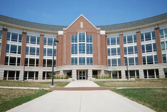 A large educational building featuring numerous windows and a connecting walkway in front.