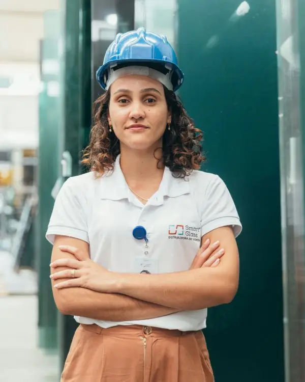 Portrait of a female factory worker wearing a hard hat, standing confidently in a manufacturing environment.
